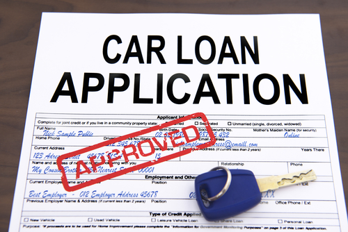 Approved car loan application form and key on desktop