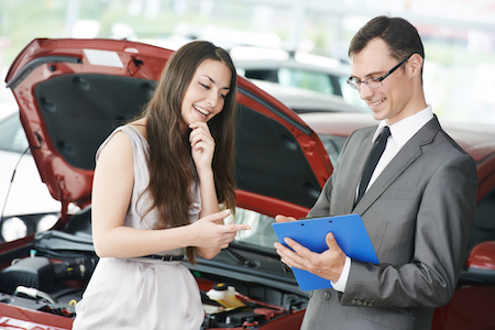 Car salesperson demonstrating new automobile to young woman