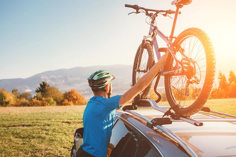 Person holding bicycle kept on the car